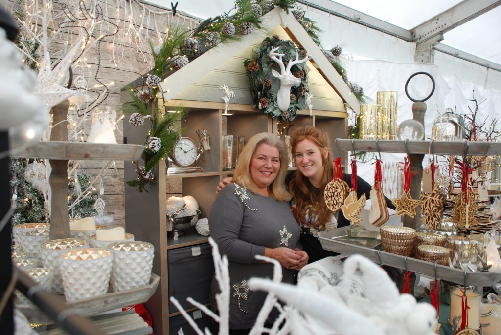 Traders at a Christmas market stall with decorations and gifts