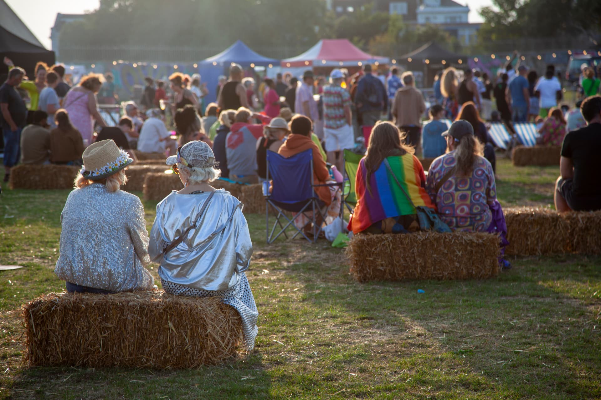 Festival crowd sitting on hay bales at sunset