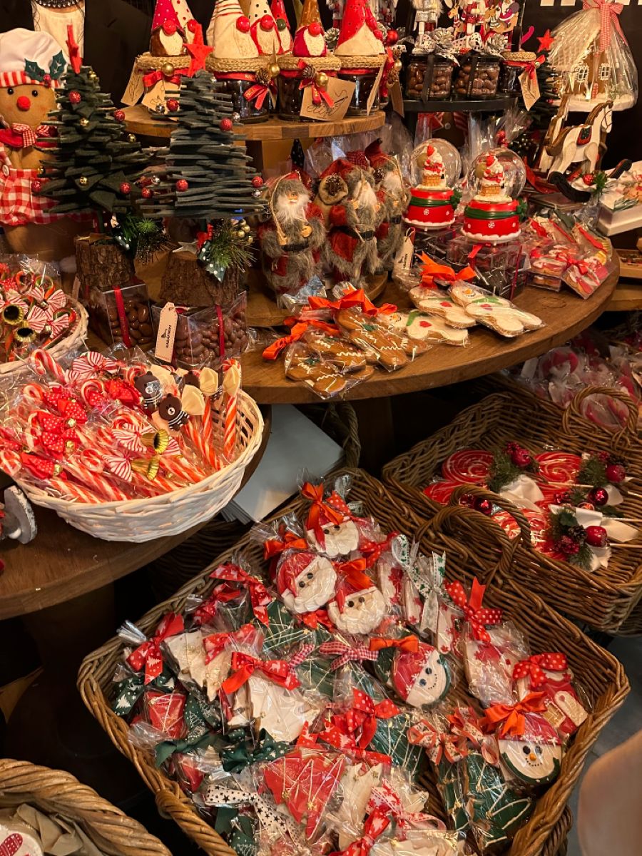 A richly laid Christmas market table of gingerbread, wrapped candy canes, Santa figurines, snow globes and baskets of festive treats