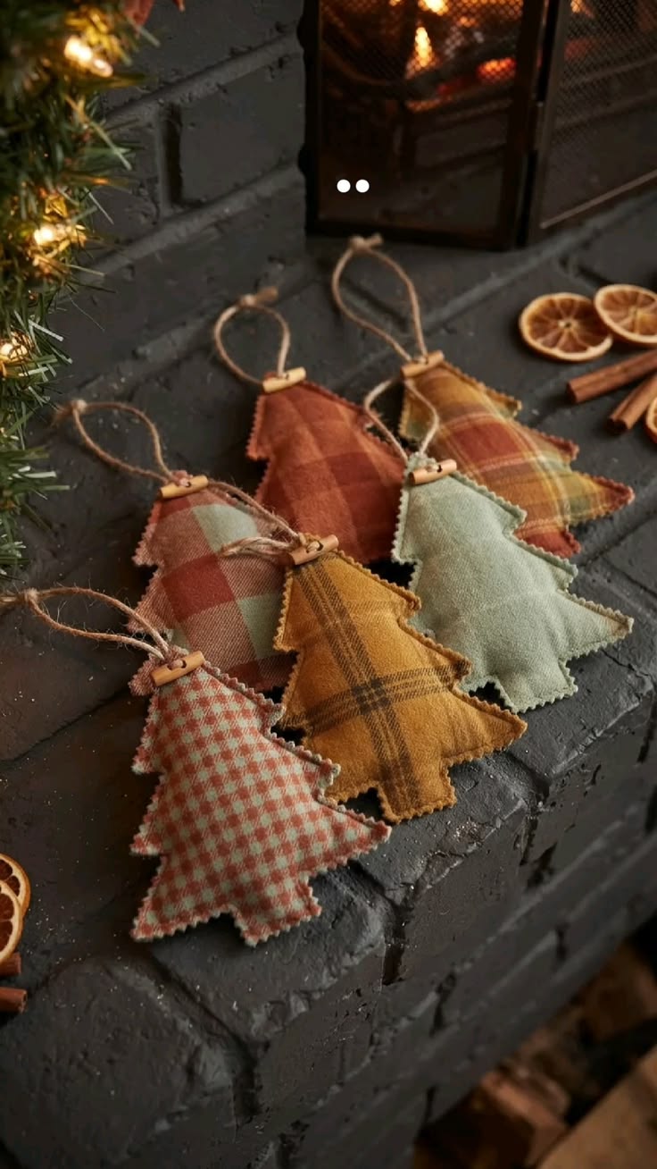 Handmade tartan and check fabric Christmas-tree ornaments beside a fireplace with dried oranges and cinnamon