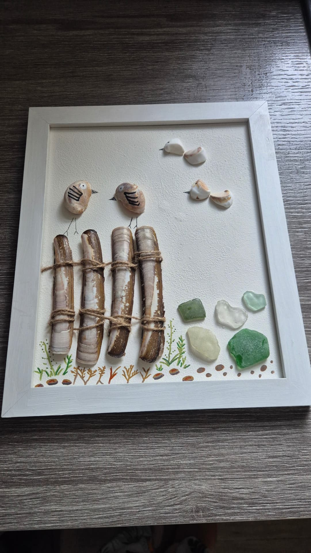 Shell-art birds on a razor shell fence with sea glass, by Saltnpixel